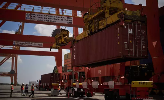 Dockworkers unload cargo containers into trucks at Umm Qasr Port, a deep-water port, in the city of Umm Qasr, Iraq, Friday, March 27, 2026. (AP Photo/Leo Correa)
