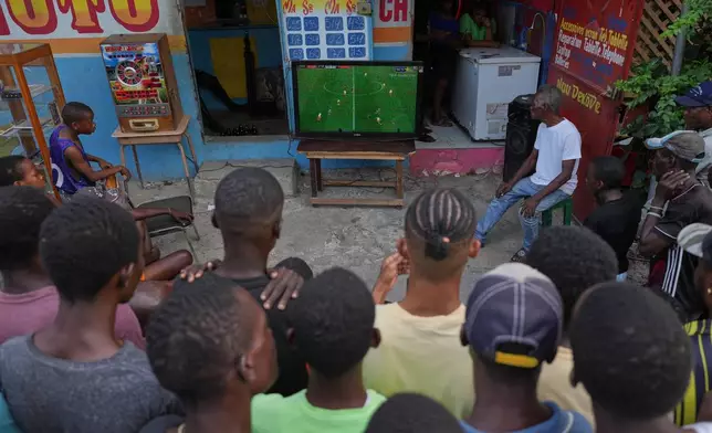 FILE - People watch a soccer match between FC Barcelona and Atlético Madrid on a sidewalk in downtown Port-au-Prince, Haiti, March 3, 2026. (AP Photo/Odelyn Joseph, File)