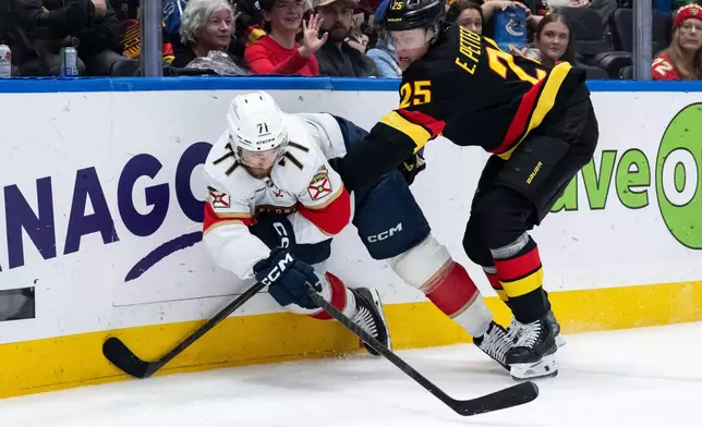 Florida Panthers' Luke Kunin passes the puck as he is hit by Vancouver Canucks' Elias Pettersson (25) during the second period of an NHL hockey game in Vancouver, on Tuesday, March 17, 2026. (Ethan Cairns/The Canadian Press via AP)