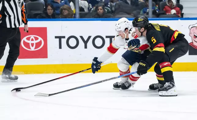Florida Panthers' Mackie Samoskevich and Vancouver Canucks' Tom Willander (5) vie for the puck during the second period of an NHL hockey game in Vancouver, Tuesday, March 17, 2026. (Ethan Cairns/The Canadian Press via AP)