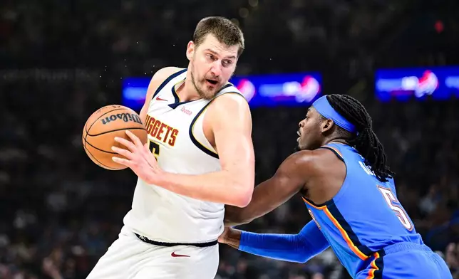 Denver Nuggets center Nikola Jokić, left, drives against Oklahoma City Thunder guard Luguentz Dort (5) during the first half of an NBA basketball game, Monday, Mar. 9, 2026, in Oklahoma City. (AP Photo/Gerald Leong)
