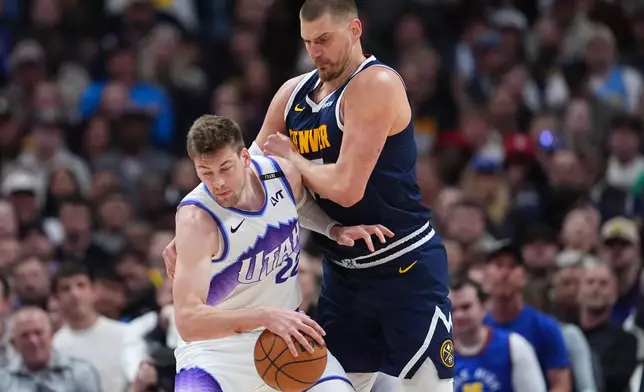 Utah Jazz center Kyle Filipowski, left, collects a loose ball as Denver Nuggets center Nikola Jokić defends in the first half of an NBA basketball game Friday, March 27, 2026, in Denver. (AP Photo/David Zalubowski)