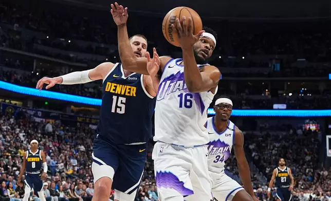Utah Jazz guard Elijah Harkless, front, pulls in a loose ball as Denver Nuggets center Nikola Jokić defends in the first half of an NBA basketball game Friday, March 27, 2026, in Denver. (AP Photo/David Zalubowski)