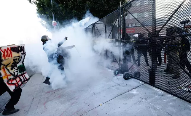 Protestors face off against police firing tear gas outside the Metropolitan Detention Center in downtown Los Angeles during a "No Kings" rally Saturday, March 28, 2026. (AP Photo/Jill Connelly)