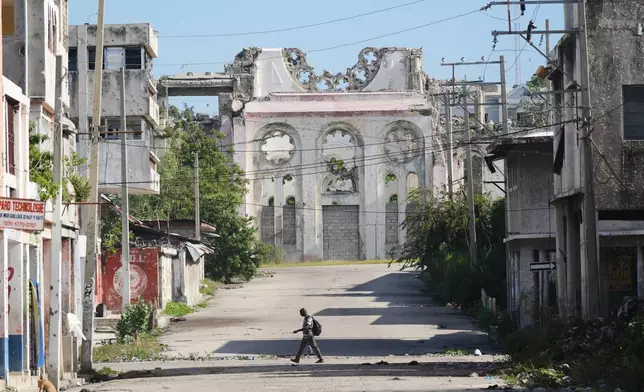 A man walks along a deserted street where a part of the earthquake-destroyed Cathedral stands in downtown Port-au-Prince, Haiti, Monday, March 16, 2026. (AP Photo/Odelyn Joseph)