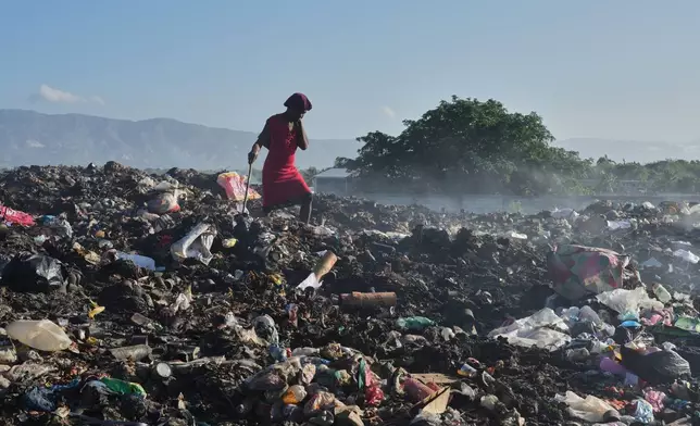 A woman searches garbage for items to use or sell in the Tabarre neighborhood of Port-au-Prince, Haiti, Monday, March 16, 2026. (AP Photo/Odelyn Joseph)