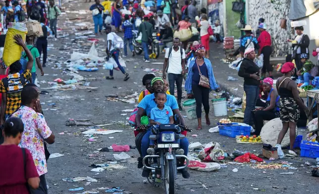 A moto-taxi driver transports clients through the Petion-Ville area of of Port-au-Prince, Haiti, Monday, March 16, 2026. (AP Photo/Odelyn Joseph)