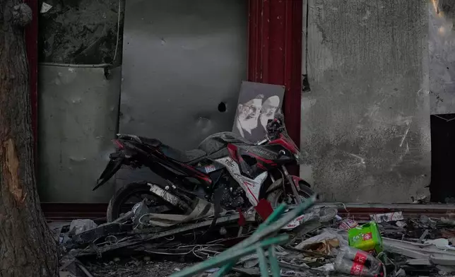 A poster of the late Supreme Leader Ayatollah Ali Khamenei, who was killed during the ongoing joint U.S.-Israeli military campaign, and the late Iranian Revolutionary founder Ayatollah Khomeini, right, lays on a motorcycle amid debris left by a strike in Tehran, Iran, Monday, March 2, 2026. (AP Photo/Vahid Salemi)