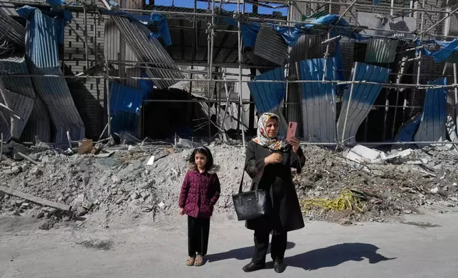 A woman takes images with her smart phone in front of a building which was damaged after a strike on a police station amid the U.S.–Israeli military campaign in Tehran, Iran, Tuesday, March 3, 2026. (AP Photo/Vahid Salemi)