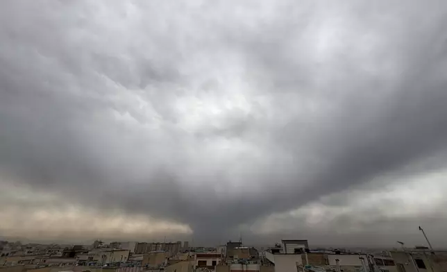 Plumes of smoke from a U.S.-Israeli strike on an oil facility late Saturday linger and merge with the cloudy sky over Tehran, Iran, Sunday, March 8, 2026. (AP Photo/Vahid Salemi)