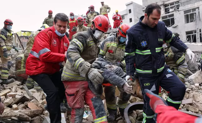 Rescue workers carry a severely injured man after pulling him from the rubble following a strike in southern Tehran, Iran, Friday, March 13, 2026. (AP Photo/Sajjad Safari)