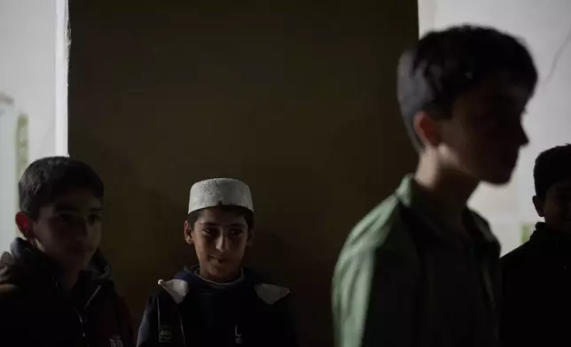 Muslim youths stand outside a mosque after the evening prayer during the holy month of Ramadan in Lajan, Iraq, Friday, March 13, 2026. (AP Photo/Leo Correa)