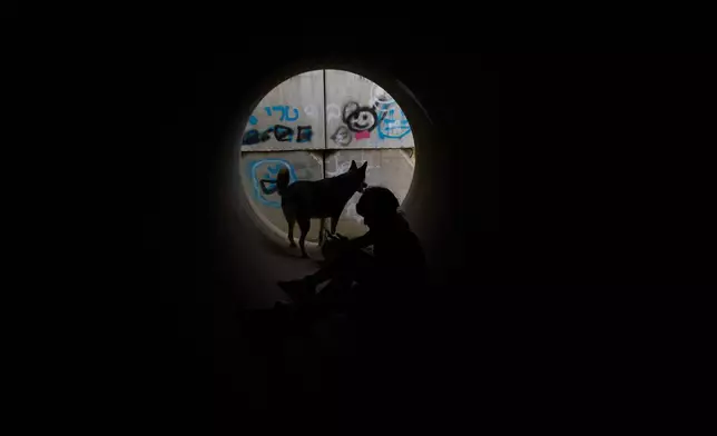 Children with a dog sit inside a cement pipe turned into a bomb shelter as air raid sirens warn of incoming Iranian missile strike in Michmoret, Israel, Saturday, March 14, 2026. (AP Photo/Ariel Schalit)