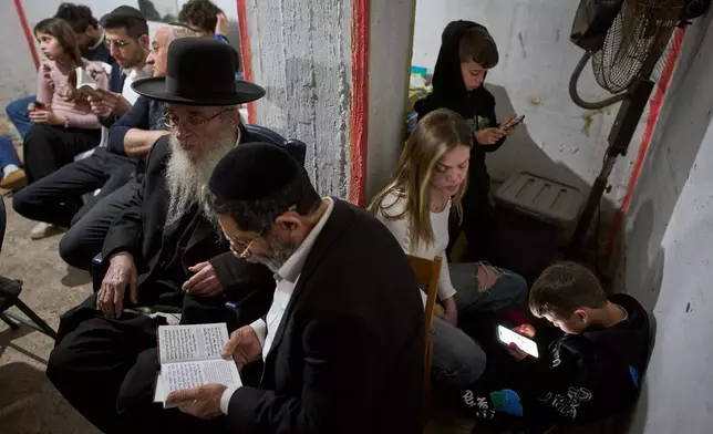 People take cover in an underground bomb shelter as air raid sirens warn of incoming Iranian missile strike, in Ramat Gan, Israel, Wednesday, March 11, 2026. (AP Photo/Oded Balilty)