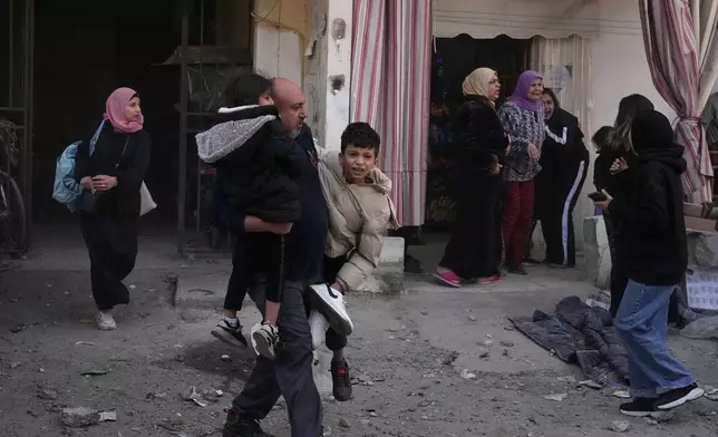 Residents flee the site of an Israeli airstrike that hit an apartment building in the southern port city of Sidon, Lebanon, Friday, March 13, 2026. (AP Photo/Mohammed Zaatari)