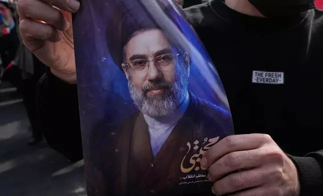A man holds a poster of Ayatollah Mojtaba Khamenei, the successor to his late father Ayatollah Ali Khamenei as supreme leader, during a rally to support him in Tehran, Iran, Monday, March 9, 2026. (AP Photo/Vahid Salemi)