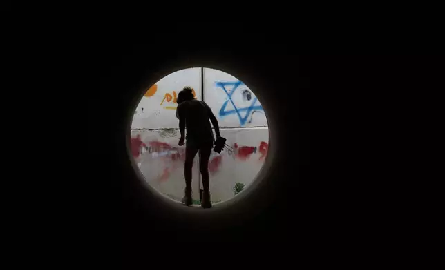 A girl walks inside a cement pipe turned into a bomb shelter as air raid sirens warn of incoming Iranian missile strike in Michmoret, Israel, Saturday, March 14, 2026. (AP Photo/Ariel Schalit)