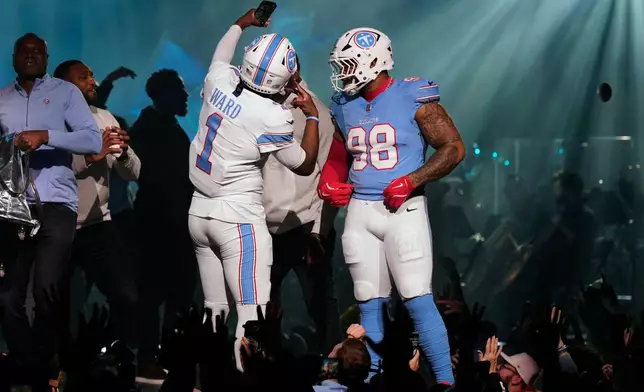 Tennessee Titans quarterback Cam Ward (1) takes a selfie with defensive tackle Jeffrey Simmons (98) as they model new uniforms during the NFL football team's event Thursday, March 12, 2026, in Nashville, Tenn. (AP Photo/George Walker IV)