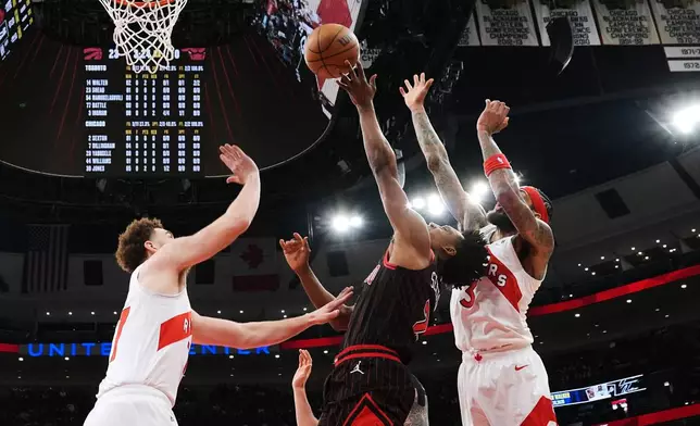 Chicago Bulls guard Collin Sexton, center, shoots against Toronto Raptors forward Jamison Battle, left, and forward Brandon Ingram during the first half of an NBA basketball game in Chicago, Wednesday, March 18, 2026. (AP Photo/Nam Y. Huh)