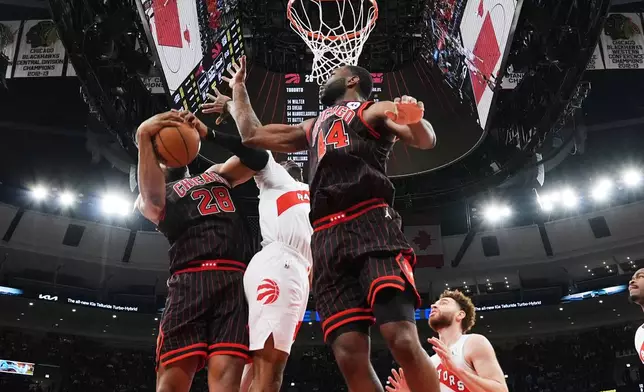 Chicago Bulls forward Guerschon Yabusele, left, battles for a rebound against forward Patrick Williams, right, and Toronto Raptors forward Brandon Ingram during the first half of an NBA basketball game in Chicago, Wednesday, March 18, 2026. (AP Photo/Nam Y. Huh)