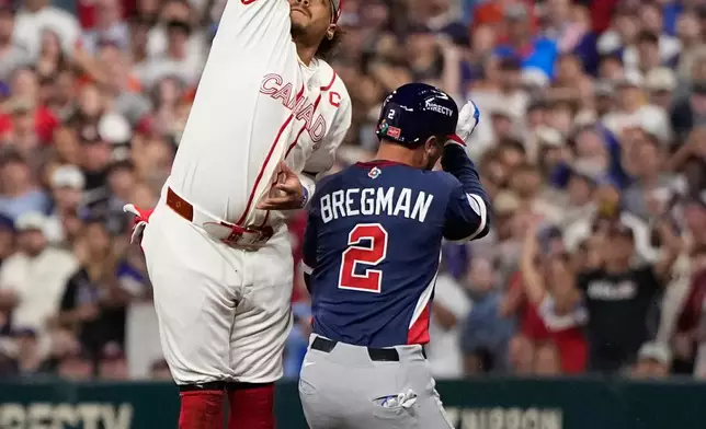 FILE - United States third baseman Alex Bregman (2) is safe at first base as Canada first baseman Josh Naylor, left, reaches for a wild throw during the third inning of a World Baseball Classic quarterfinal game, March 13, 2026, in Houston. (AP Photo/David J. Phillip, File)