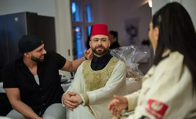 Haidar Darwish, a belly dancer and artist who came from Syria, center, attends an inclusive Iftar, the Ramadan fast-breaking meal, with friends who are Muslim, Christian, queer and straight, in Berlin, Germany, Wednesday, March 11, 2026. (AP Photo/Ebrahim Noroozi)