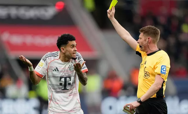 Referee Christian Dingert shows a yellow card to Bayern's Luis Diaz during a German Bundesliga soccer match between Bayer Leverkusen and Bayern Munich in Leverkusen, Germany, Saturday, March 14, 2026. (AP Photo/Martin Meissner)