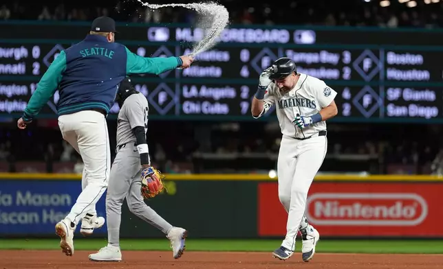Seattle Mariners' Luke Raley, left, throws water on Cal Raleigh to celebrate Raleigh's game-winning single as New York Yankees second baseman Jazz Chisholm Jr. walks away after a baseball game, Monday, March 30, 2026, in Seattle. (AP Photo/Lindsey Wasson)