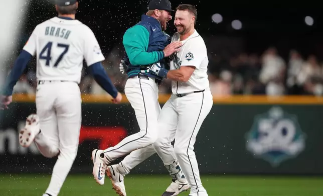 Seattle Mariners' Luke Raley celebrates with Cal Raleigh, right, after Raleigh's game-winning single against the New York Yankees after a baseball game, Monday, March 30, 2026, in Seattle. (AP Photo/Lindsey Wasson)