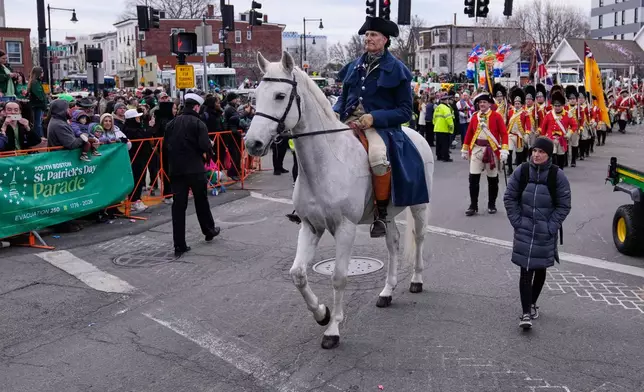 A rider portraying Paul Revere is followed by re-enactors marching as Revolutionary War British soldiers in red coats during the annual St. Patrick's Day parade through the South Boston neighborhood, Sunday, March 15, 2026, in Boston. (AP Photo/Charles Krupa)
