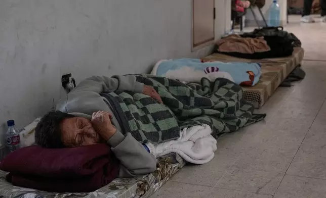 A displaced woman who fled Israeli airstrikes in southern Lebanon sleeps on the ground at the Bir Hassan Technical Institute, which has been turned into a shelter, in Beirut, Lebanon, Wednesday, March 11, 2026. (AP Photo/Bilal Hussein)