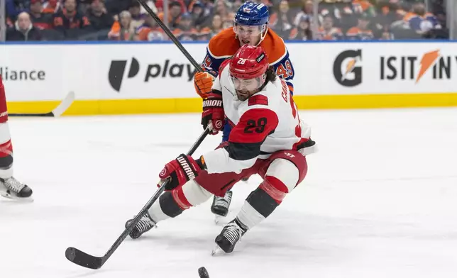 Carolina Hurricanes' William Carrier (28) and Edmonton Oilers' Ty Emberson (49) battle for the puck during second-period NHL hockey game action in Edmonton, Alberta, Friday March 6, 2026. (Jason Franson/The Canadian Press via AP)