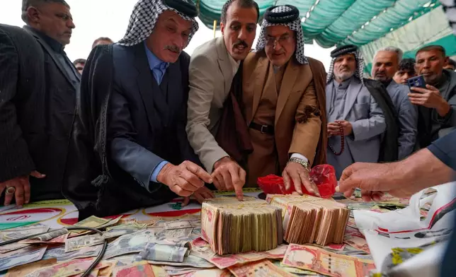 People donate money following a call by Grand Ayatollah Ali al-Sistani to support Iran and Lebanon during the war with the U.S. and Israel, Friday, March 27, 2026, in Babylon, Iraq. (AP Photo/Anmar Khalil)