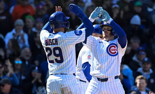 Chicago Cubs' Ian Happ, right, high-fives Michael Busch (29) after they score on Happ's three run home run during the sixth inning of a baseball game against the Washington Nationals, Saturday, March 28, 2026, in Chicago. (AP Photo/Matt Marton)