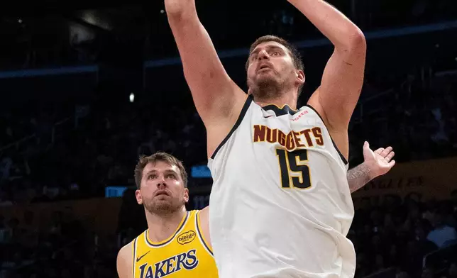 Denver Nuggets center Nikola Jokic, right, shoots past Los Angeles Lakers guard Luka Doncic during the first half of an NBA basketball game in Los Angeles, Saturday, March 14, 2026. (AP Photo/Kyusung Gong)