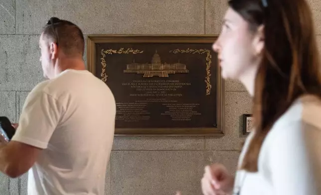 A tour group walks by a plaque honoring police service on Jan. 6, 2021 at the Capitol, Saturday, March 7, 2026, in Washington. (AP Photo/Allison Robbert)