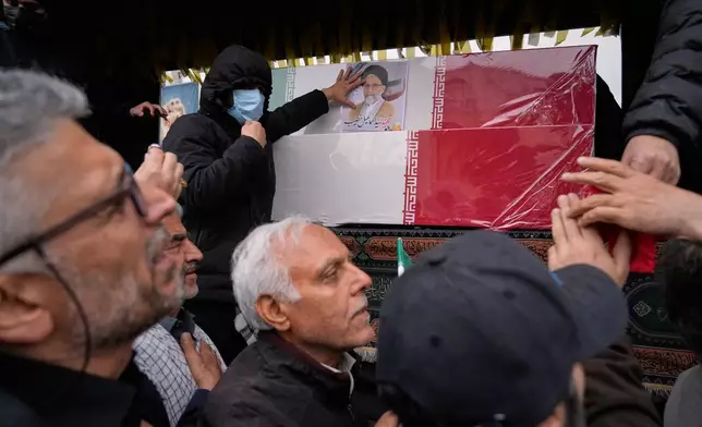 Iranians reach toward the coffins as they follow the funeral procession of Iran's intelligence minister Esmail Khatib and, according to Iranian officials, his wife and daughter, in Tehran, Iran, Friday, March 20, 2026. (AP Photo/Vahid Salemi)