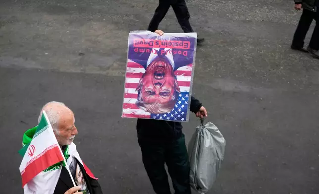 A man holds a picture of U.S. President Donald Trump upside down after Friday prayers at the Imam Khomeini Grand Mosque in Tehran, Iran, Friday, March 20, 2026. (AP Photo/Vahid Salemi)