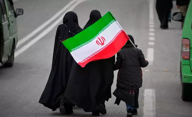 Two women and a child holding an Iranian flag walk toward the Imam Khomeini Grand Mosque to attend Friday prayers in Tehran, Iran, Friday, March 20, 2026. (AP Photo/Vahid Salemi)