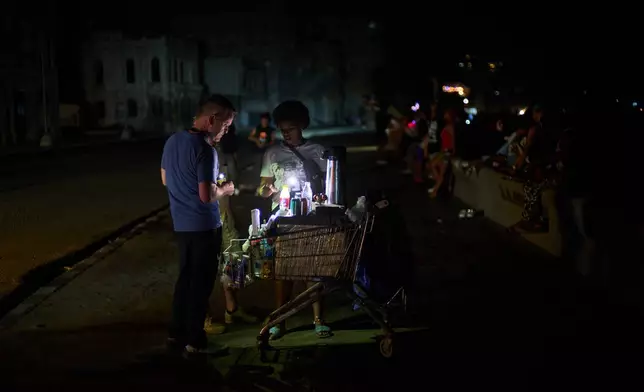 A street vendor tends to a customer on the Malecón during a blackout in Havana, Monday, March 16, 2026. (AP Photo/Ramon Espinosa)