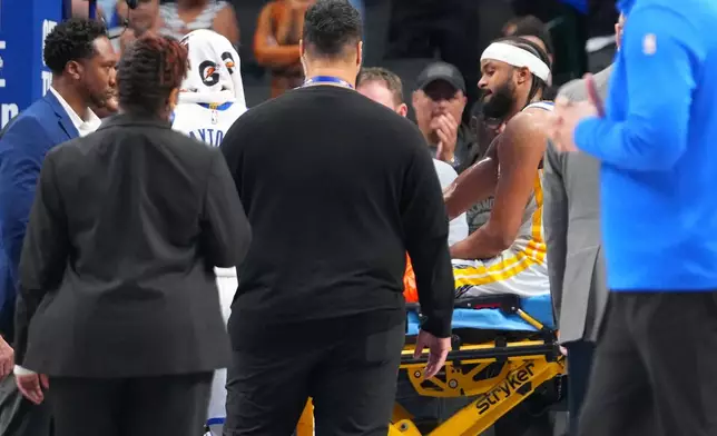 Golden State Warriors guard Moses Moody is carted off the field after suffering an injury against the Dallas Mavericks during overtime of an NBA basketball game Monday, March 23, 2026, in Dallas. (AP Photo/Julio Cortez)