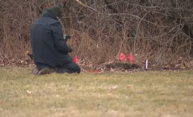 This image made from video provided by WEWS/News 5 shows an official examining a crime scene where the bodies of two young girls were found buried in suitcases, Tuesday, March 3, 2026, in Cleveland. (WEWS/News 5 via AP)