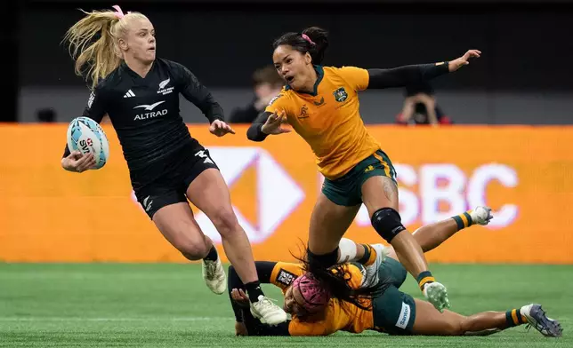 New Zealand's Jorja Miller, left, prepares to pass the ball as she is tackled by Australia's Amahli Hala, back, and Faith Nathan (3) watches during gold medal Vancouver Sevens women's rugby action, in Vancouver, on Sunday, March 8, 2026. (Ethan Cairns/The Canadian Press via AP)