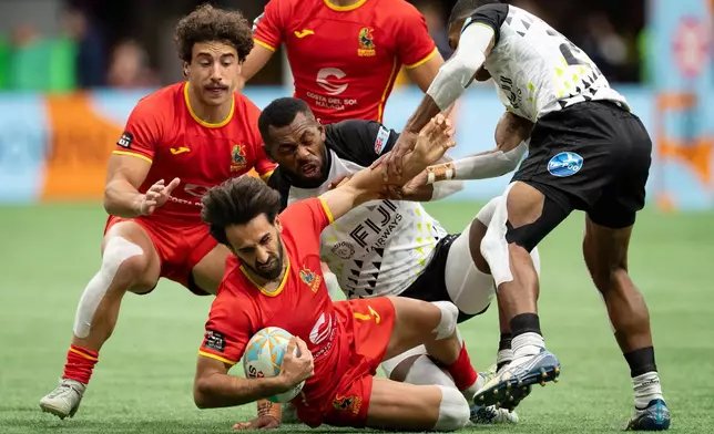 Spain's Pol Pla, front center, is stopped by Fiji's Sevuloni Mocenacagi, centre, and Douglas Daveta, right, as Spain's Josep Serres (2) watches during Vancouver Sevens semifinal rugby action, in Vancouver, on Sunday, March 8, 2026. (Ethan Cairns/The Canadian Press via AP)