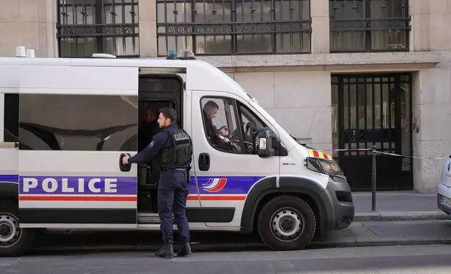 Police stand outside the Bank of America building in Paris, Saturday, March 28, 2026. (AP Photo/Nicolas Garriga)