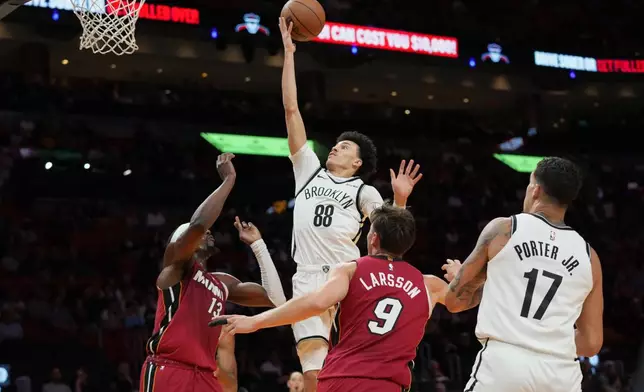Brooklyn Nets guard Nolan Traore (88) goes to the basket as Miami Heat center Bam Adebayo (13) and guard Pelle Larsson (9) defend during the first half of an NBA basketball game, Thursday, March 5, 2026, in Miami. (AP Photo/Lynne Sladky)