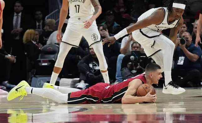 Miami Heat guard Tyler Herro falls to the court as Brooklyn Nets guard Terance Mann, right, defends during the first half of an NBA basketball game, Thursday, March 5, 2026, in Miami. (AP Photo/Lynne Sladky)