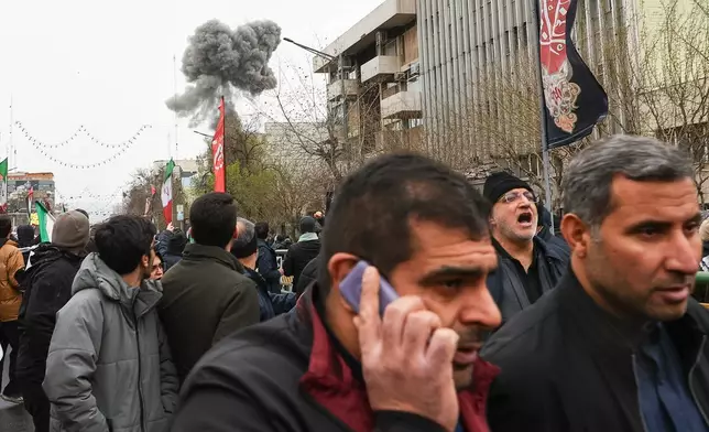 Smoke from an explosion rises behind demonstrators attending the annual anti-Israeli Quds Day, or Jerusalem Day, rally in support of Palestinians in Tehran, Iran, Friday, March 13, 2026. (Mohammad Mahdi Dehghani/Fars News Agency via AP)