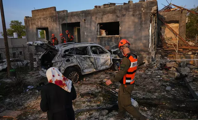 Residents and officers from Israel's Home Front Command inspect a house destroyed by an Iranian missile strike in Zarzir, northern Israel, Friday, March 13, 2026. (AP Photo/Ariel Schalit)