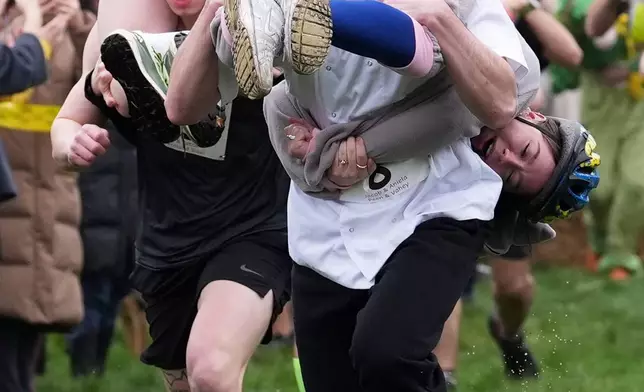 People take part in the annual UK Wife Carrying Race in Dorking, England, Sunday March 8, 2026. (Gareth Fuller/PA via AP)
